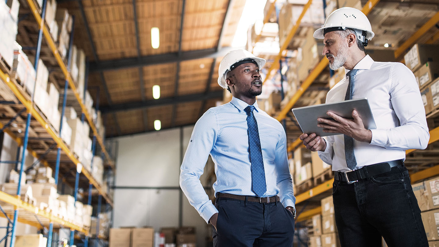 two project managers meeting up while using a tablet banner